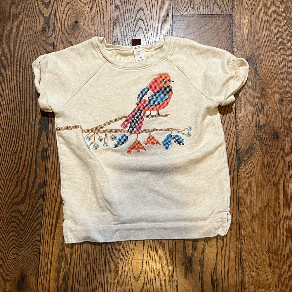 A white shirt with a colorful bird on it